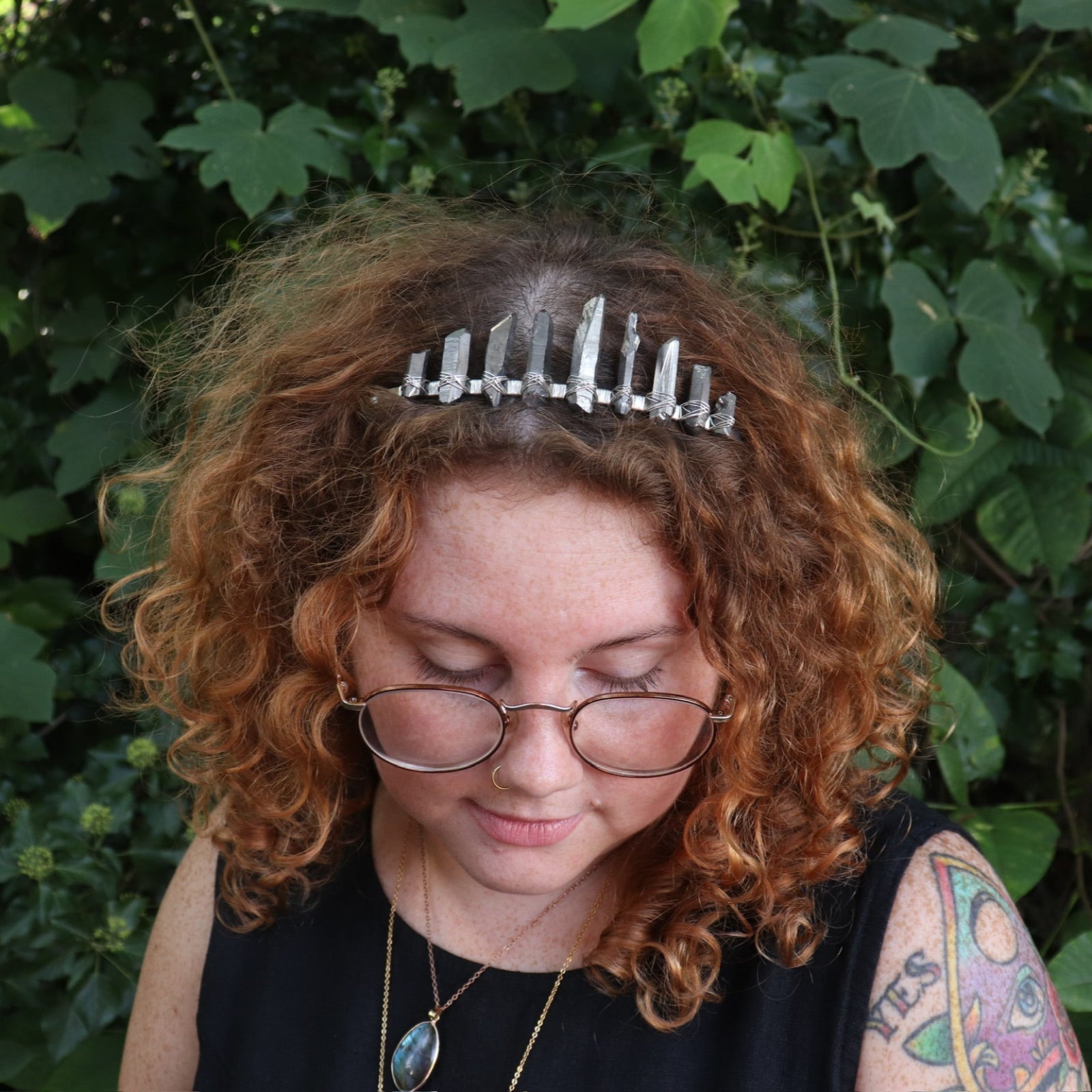 A woman wearing the Fairy Crown / Celtic Tiara - Titanium Quartz in front of greenery.