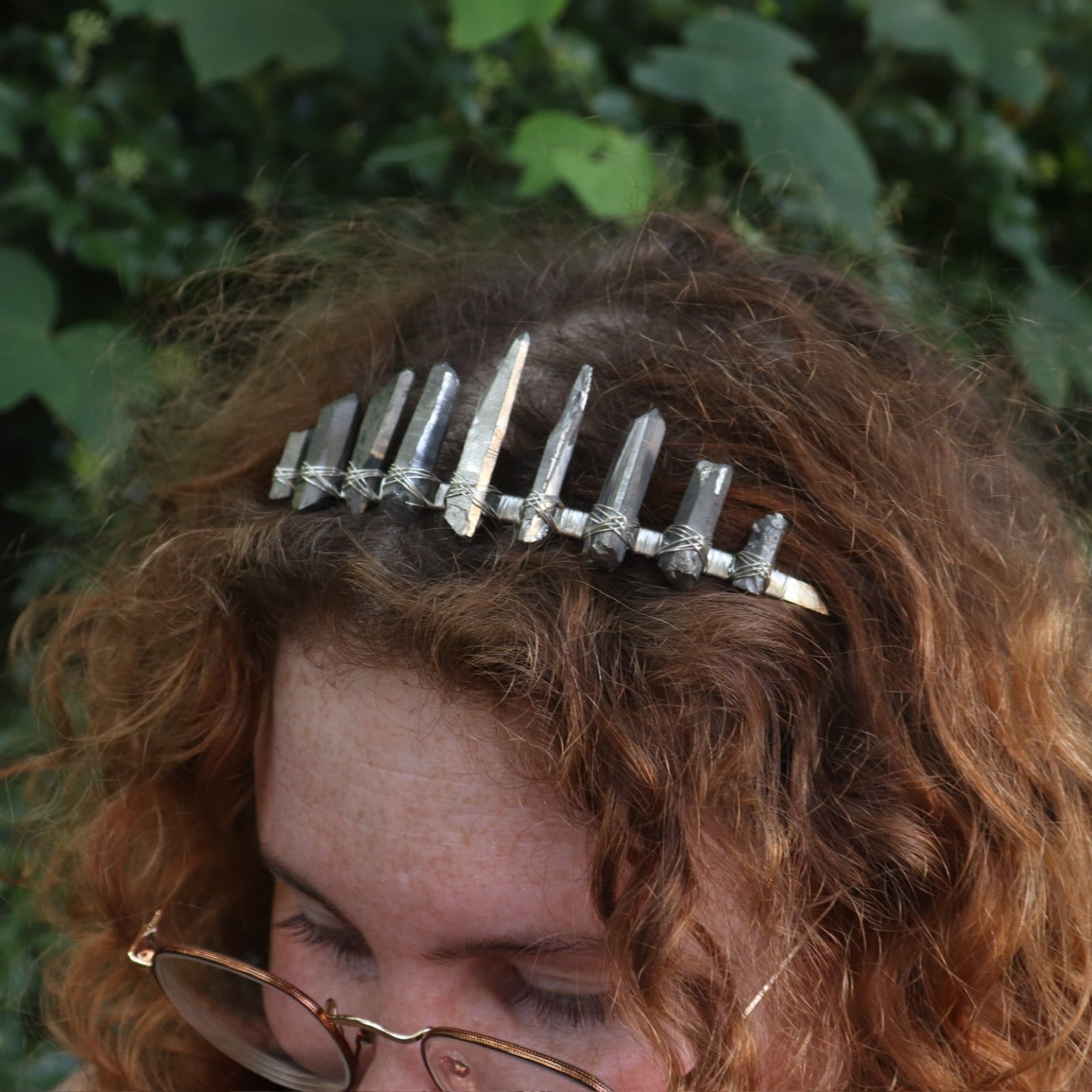 A woman wearing the Fairy Crown / Celtic Tiara - Titanium Quartz in front of greenery.