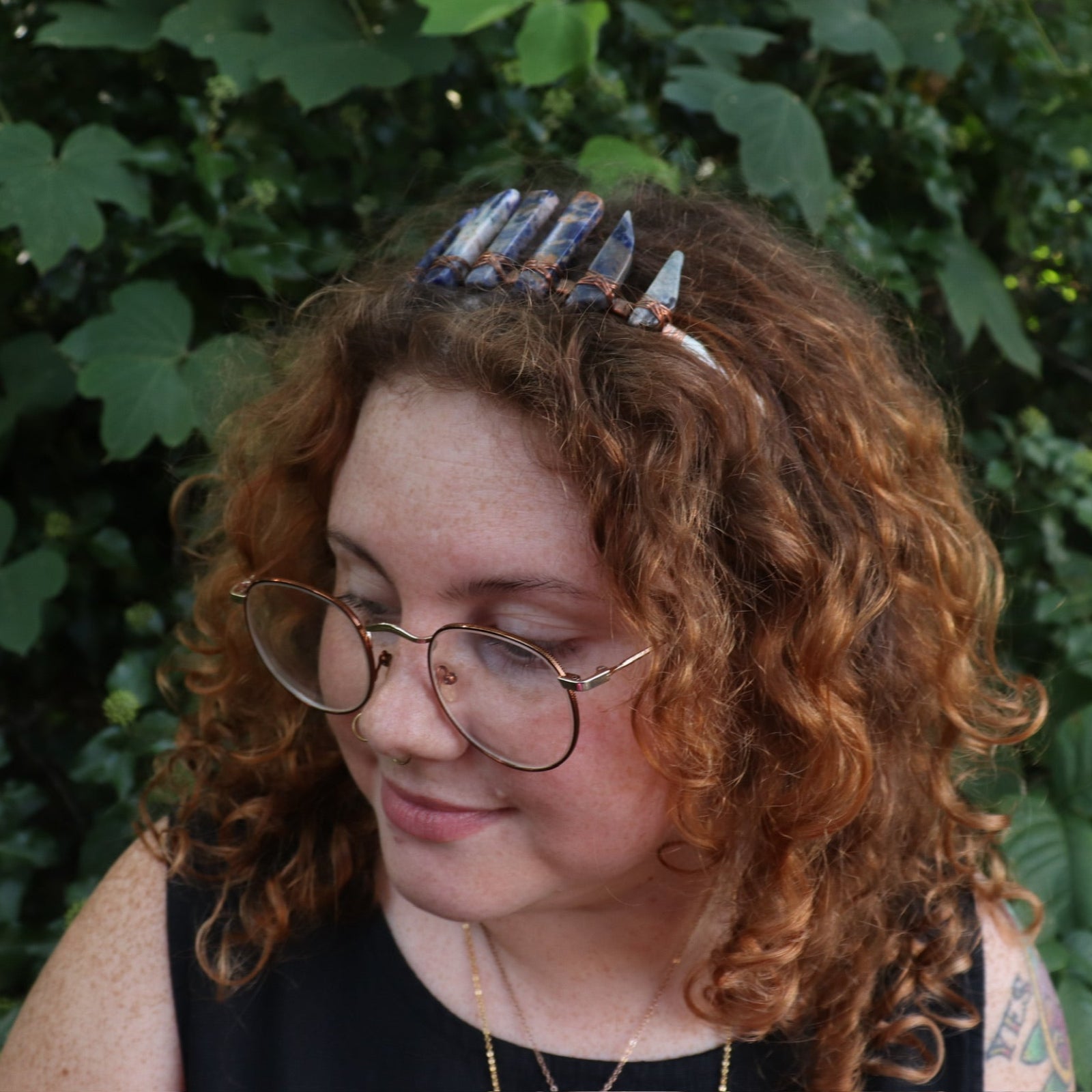 A woman wearing the Fairy Crown / Celtic Tiara - Orange & Blue Sodalite in front of greenery.