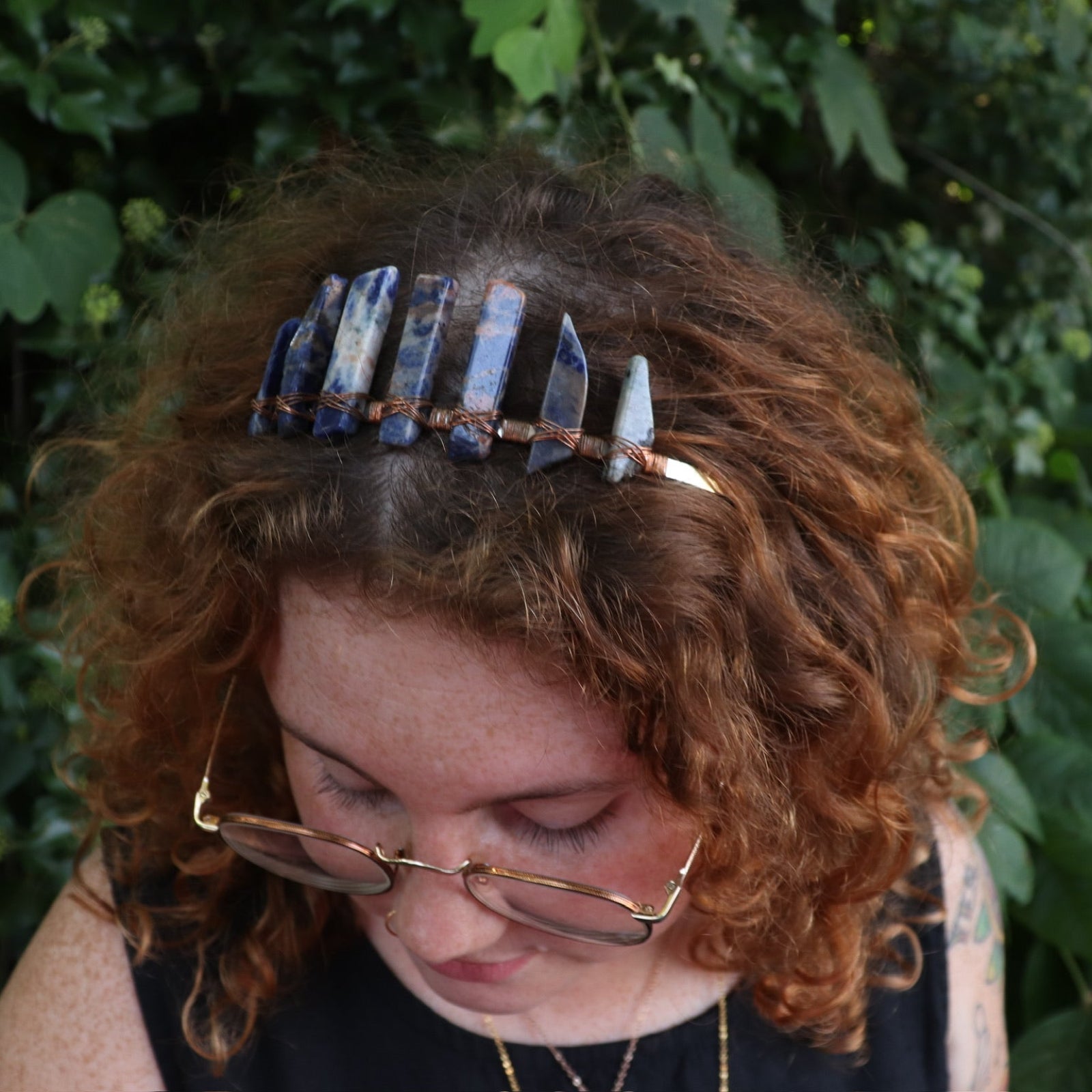 A woman wearing the Fairy Crown / Celtic Tiara - Orange & Blue Sodalite in front of greenery.