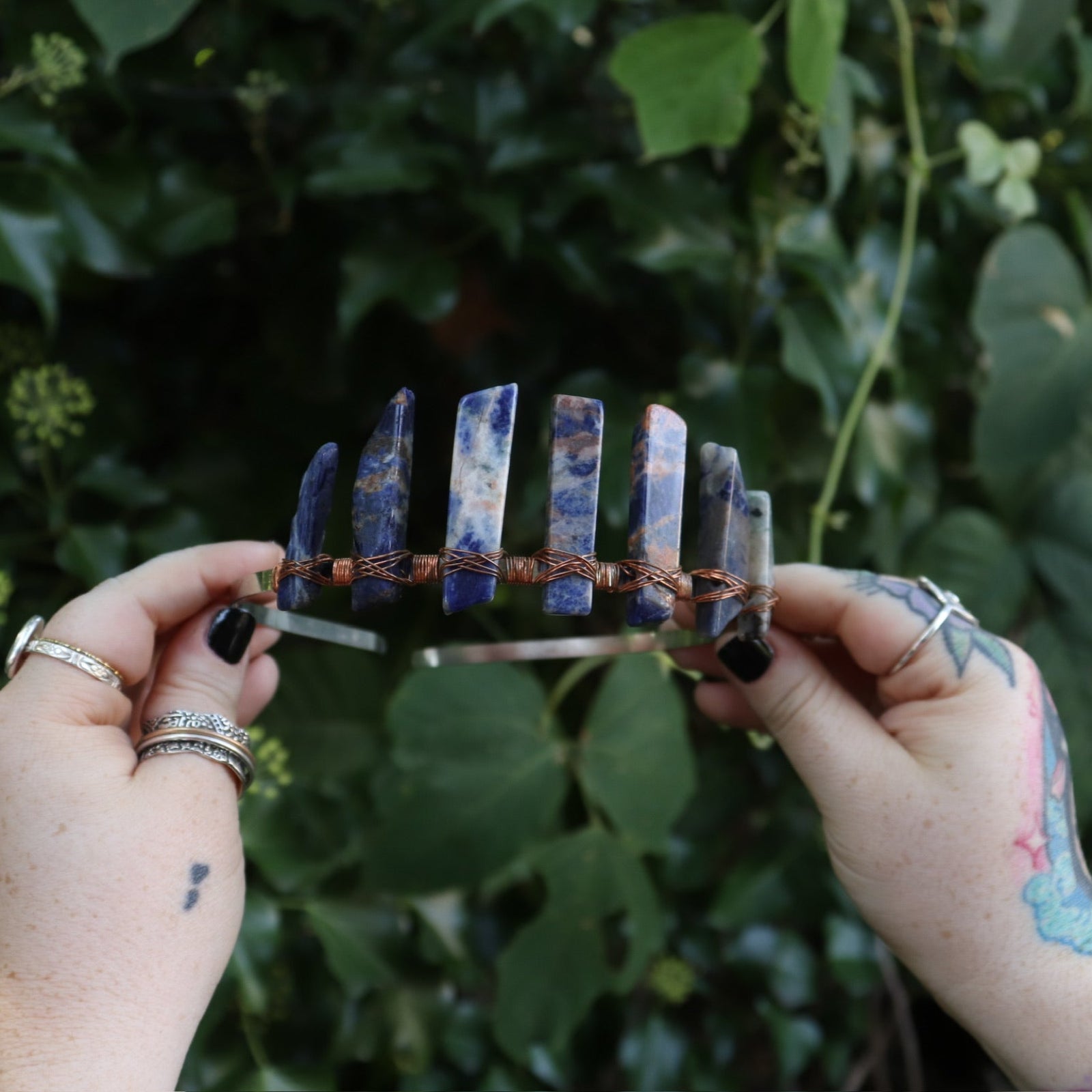 Someone holding the Fairy Crown / Celtic Tiara - Orange & Blue Sodalite in front of greenery.