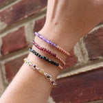 Someone wearing all the crystal faceted beads + Copper Bracelets in front of a brick wall.