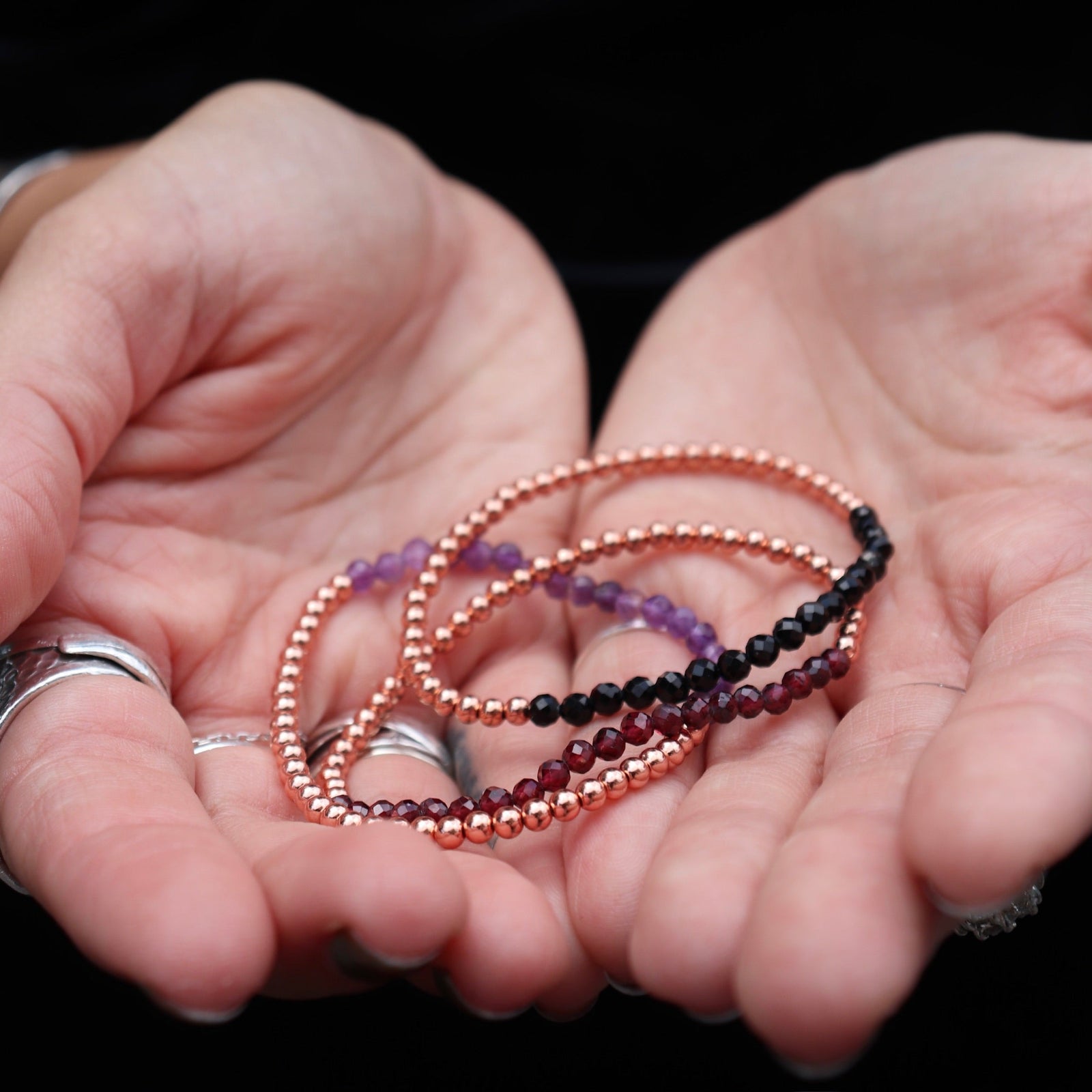 Someone holding all the crystal faceted beads + Copper Bracelets.