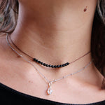 Someone wearing the Dainty 4mm Faceted Black Tourmaline Cord 16"-18" Necklace  with another silver necklace.