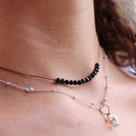 Someone wearing the Dainty 4mm Faceted Black Tourmaline Cord 16"-18" Necklace  with another silver necklace.