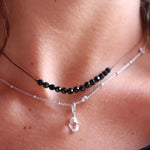 Someone wearing the Dainty 4mm Faceted Black Tourmaline Cord 16"-18" Necklace  with another silver necklace.