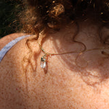 A woman wearing the Mini Rose Quartz Crystal Pendulum Necklace, showing off the back.