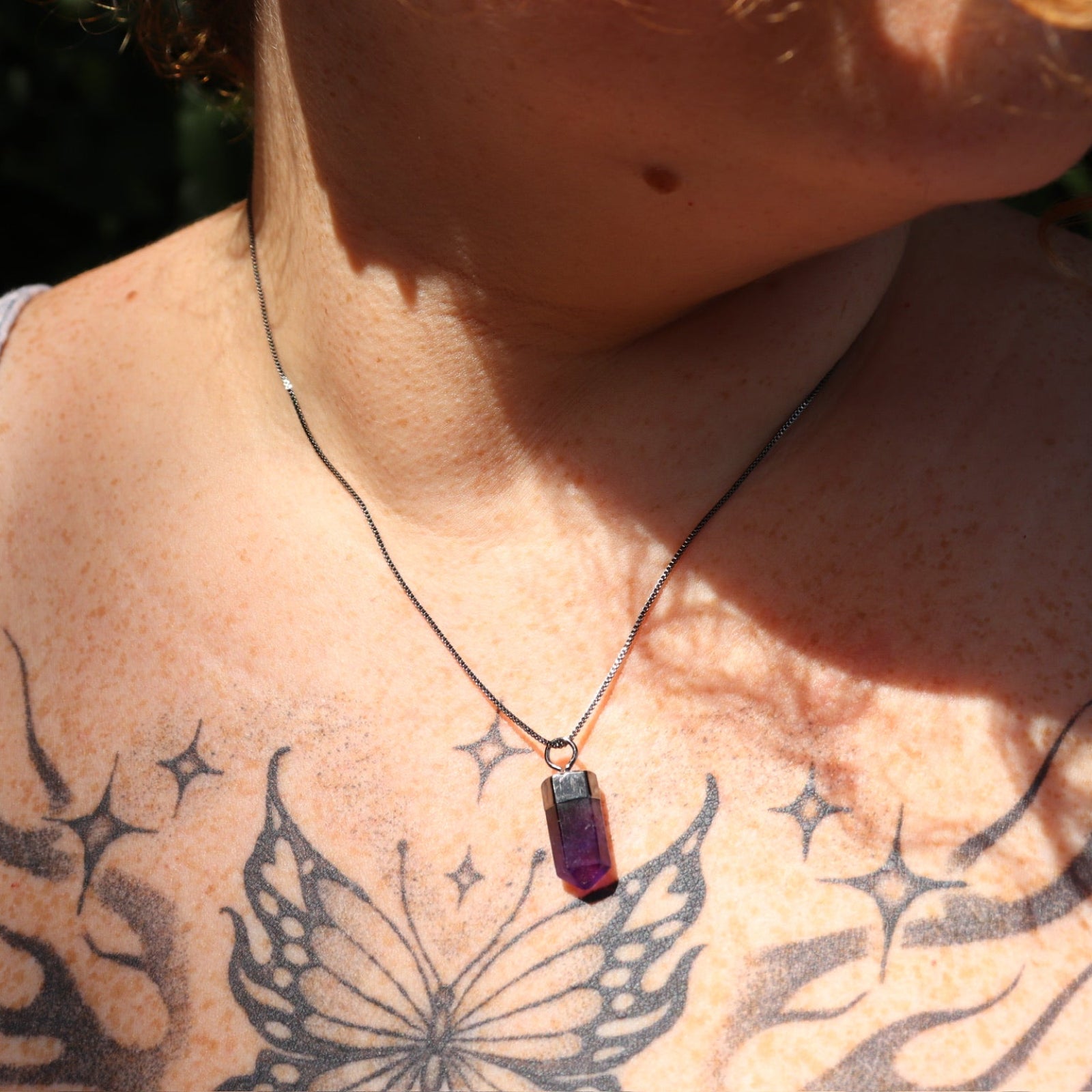 Someone wearing the Mini Amethyst Crystal Pendulum Necklace.