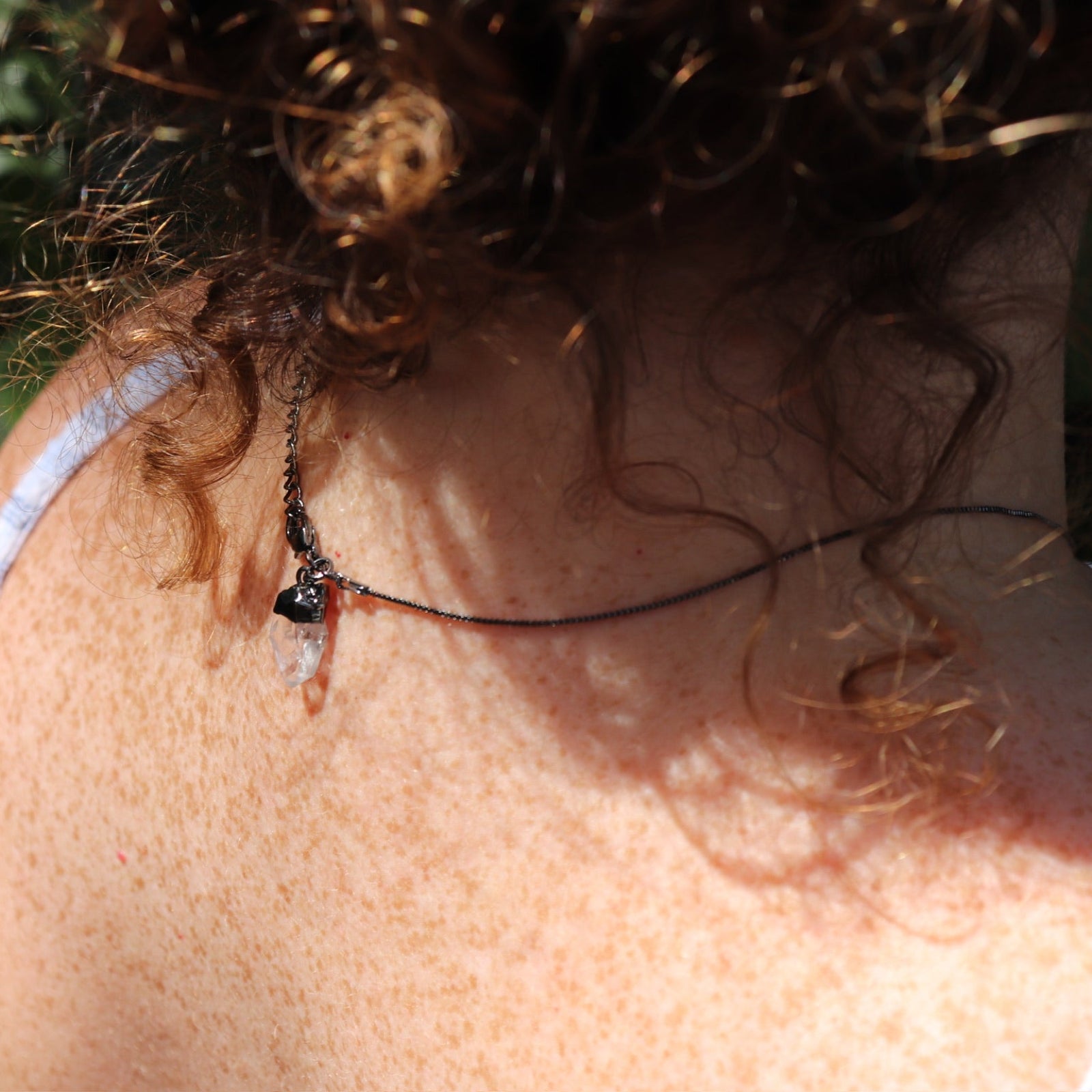 Someone wearing the Mini Amethyst Crystal Pendulum Necklace ,showing off the back.