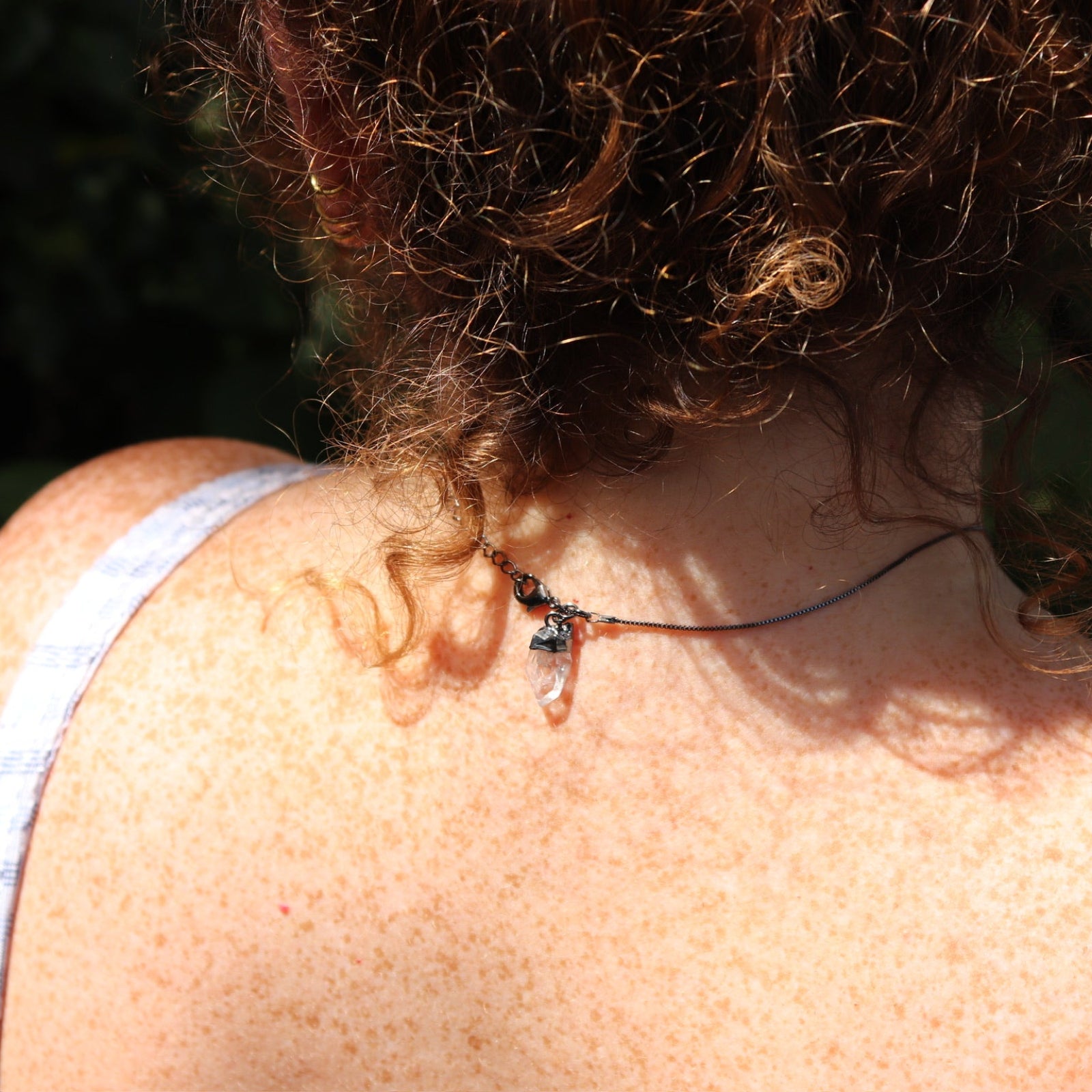 Someone wearing the Mini Amethyst Crystal Pendulum Necklace ,showing off the back.