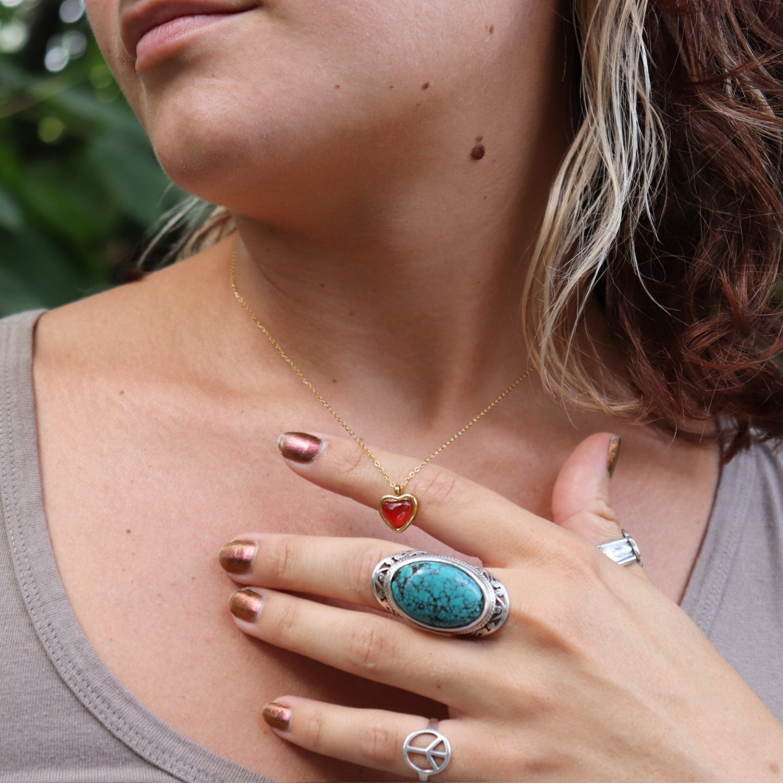 A woman wearing the gold necklace from the Carnelian Earrings & Necklace Gift Jewelry Set.