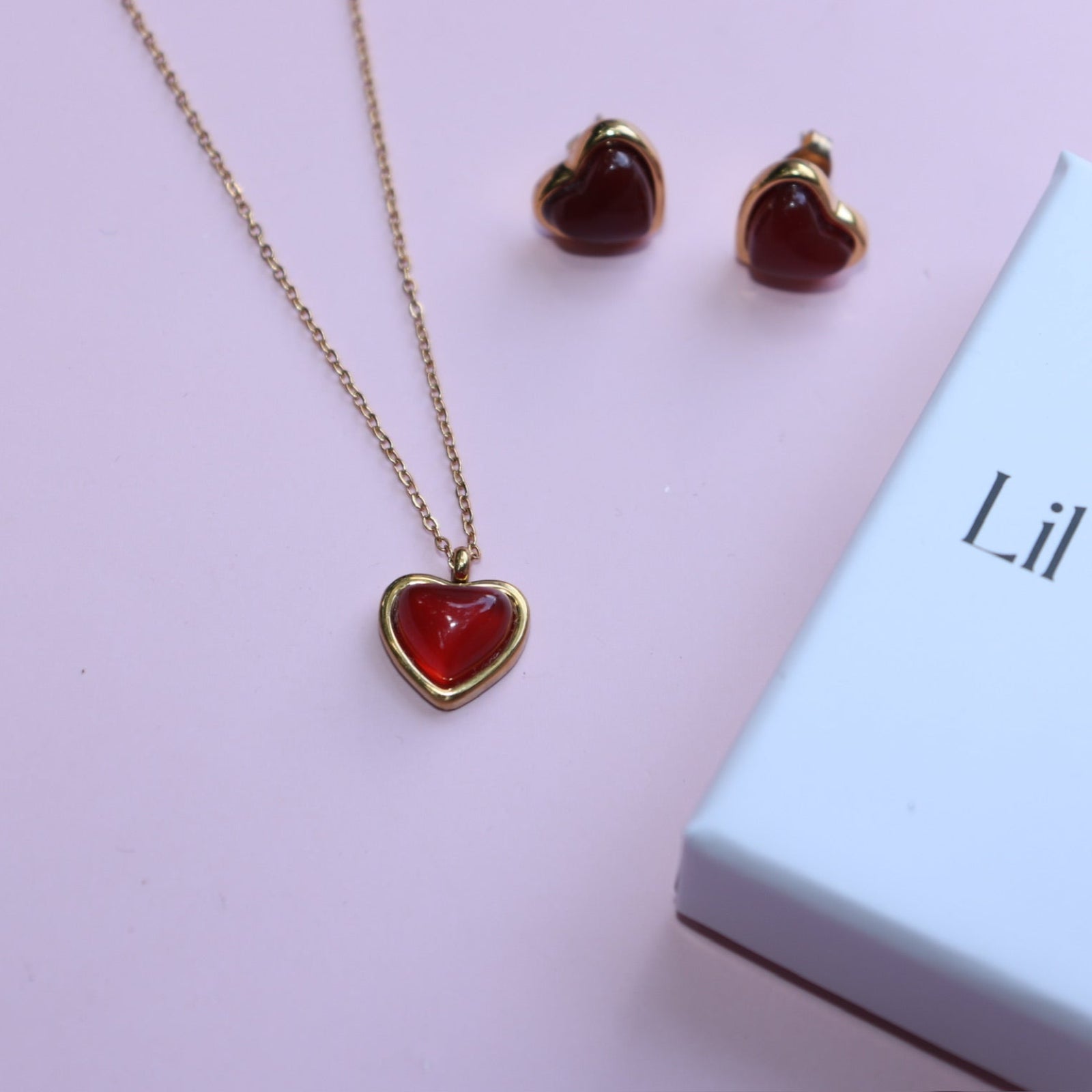 The gold Carnelian Earrings & Necklace Gift Jewelry Set on a pink background.