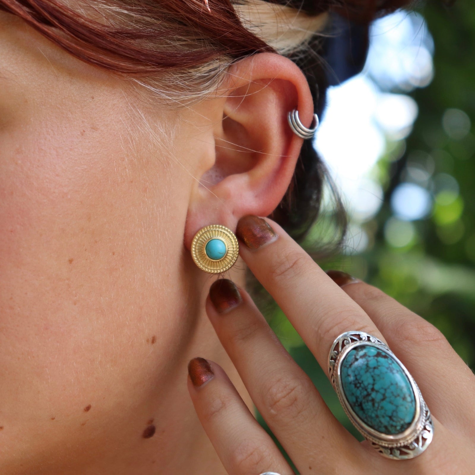 Someone wearing the Turquoise Gold Stud Earrings.