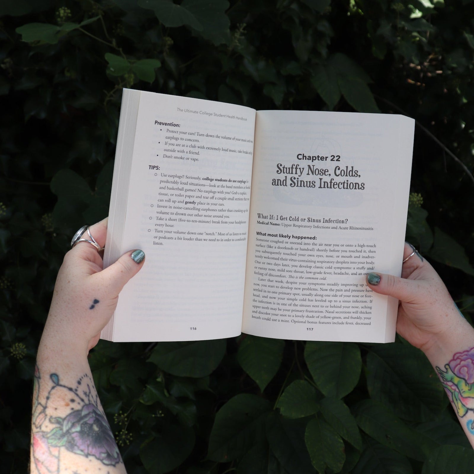 Someone holding the Ultimate College Student Health Handbook by Jill Grimes open in front of greenery, showing off the pages.