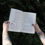 Someone holding the Ultimate College Student Health Handbook by Jill Grimes open in front of greenery, showing off the pages.