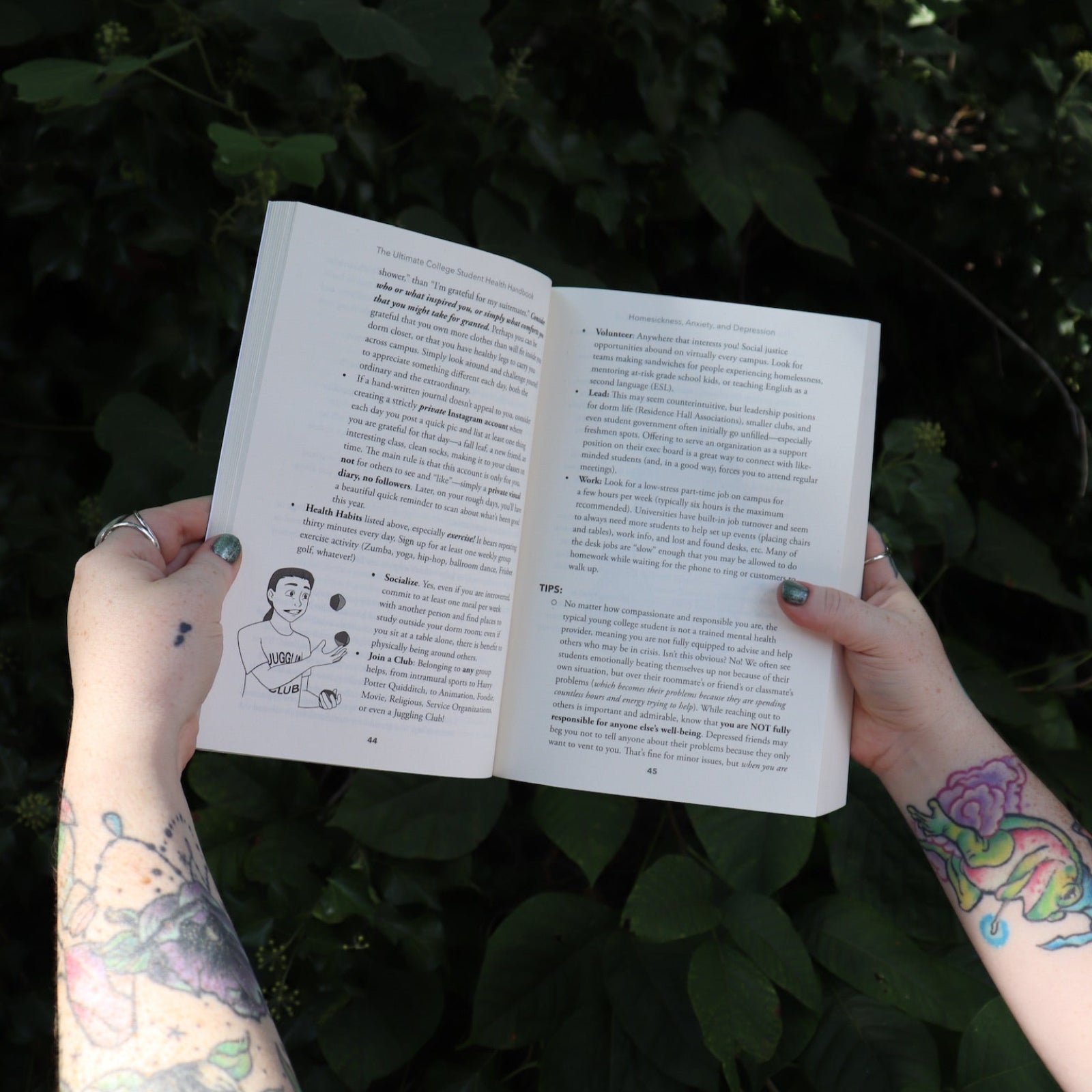 Someone holding the Ultimate College Student Health Handbook by Jill Grimes open in front of greenery, showing off the pages.