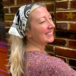 A woman wearing the Screenprinted Chat Noir Cotton Bandana around her head.