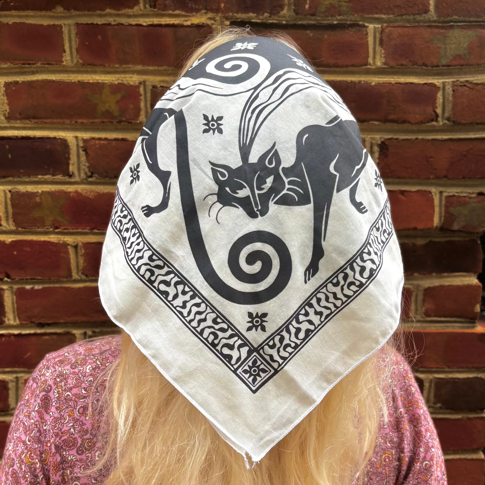 A woman wearing the Screenprinted Chat Noir Cotton Bandana around her head.