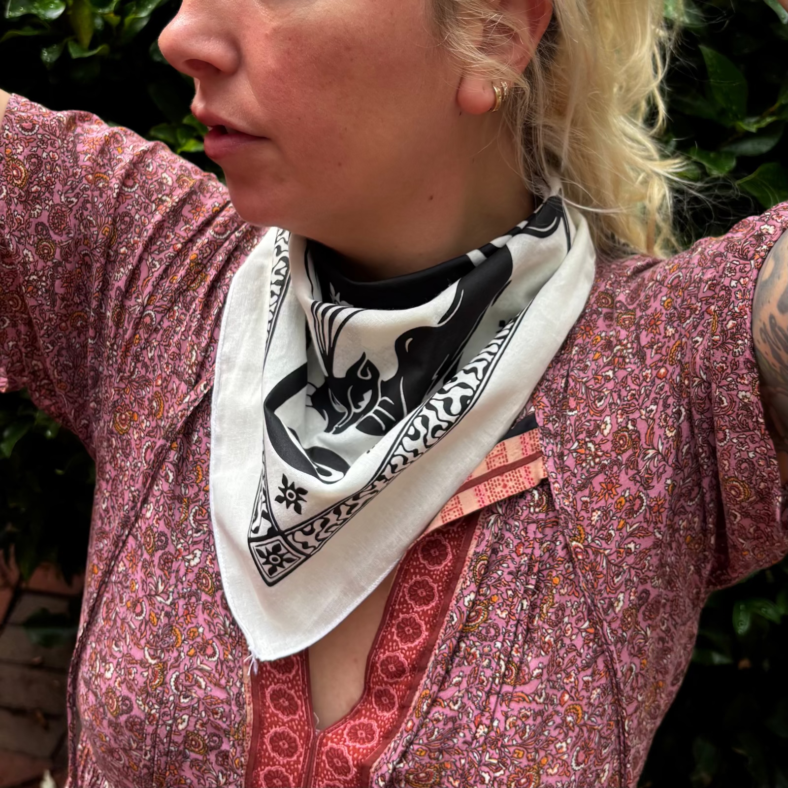 A woman wearing the Screenprinted Chat Noir Cotton Bandana around her neck.