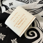 An up close image of the packaging on the Screenprinted Chat Noir Cotton Bandana.