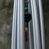 An up-close image of someone holding up the Seven Stone Blue Woodstock Chakra Chime in front of a concrete wall.
