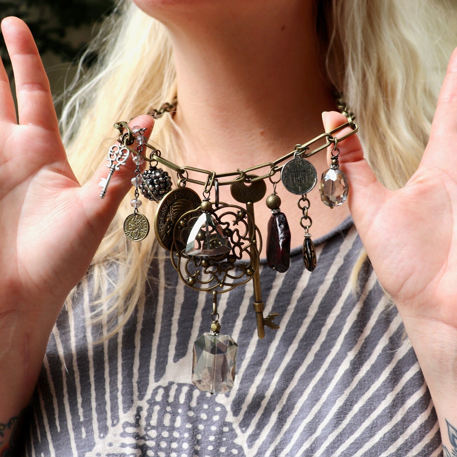 A woman wearing the Gypsy Junk Original-Gray 24" Necklace and holding it up to show individual charms.