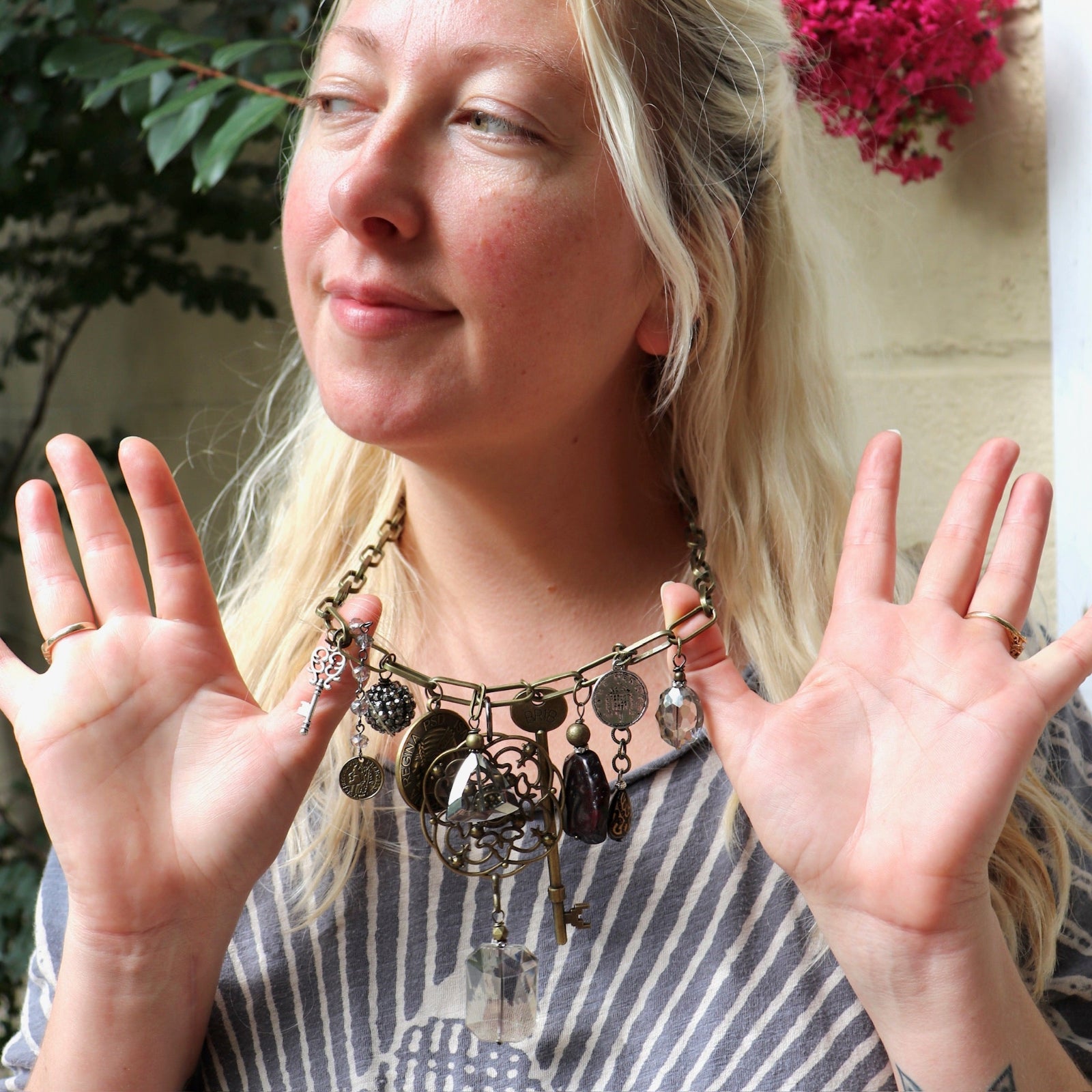 A woman wearing the Gypsy Junk Original-Gray 24" Necklace and holding it up to show individual charms.