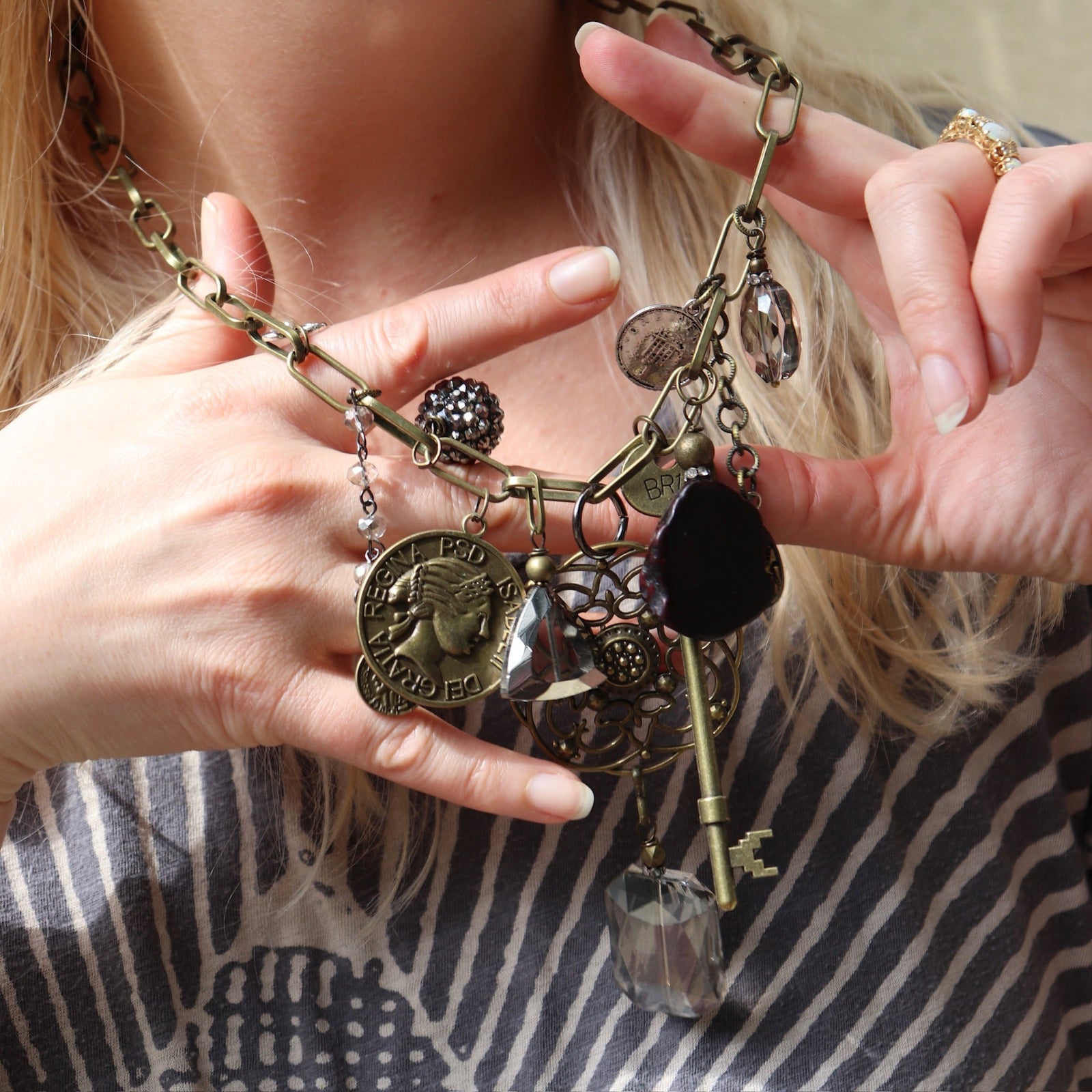 A woman wearing the Gypsy Junk Original-Gray 24" Necklace and holding it up to show individual charms.