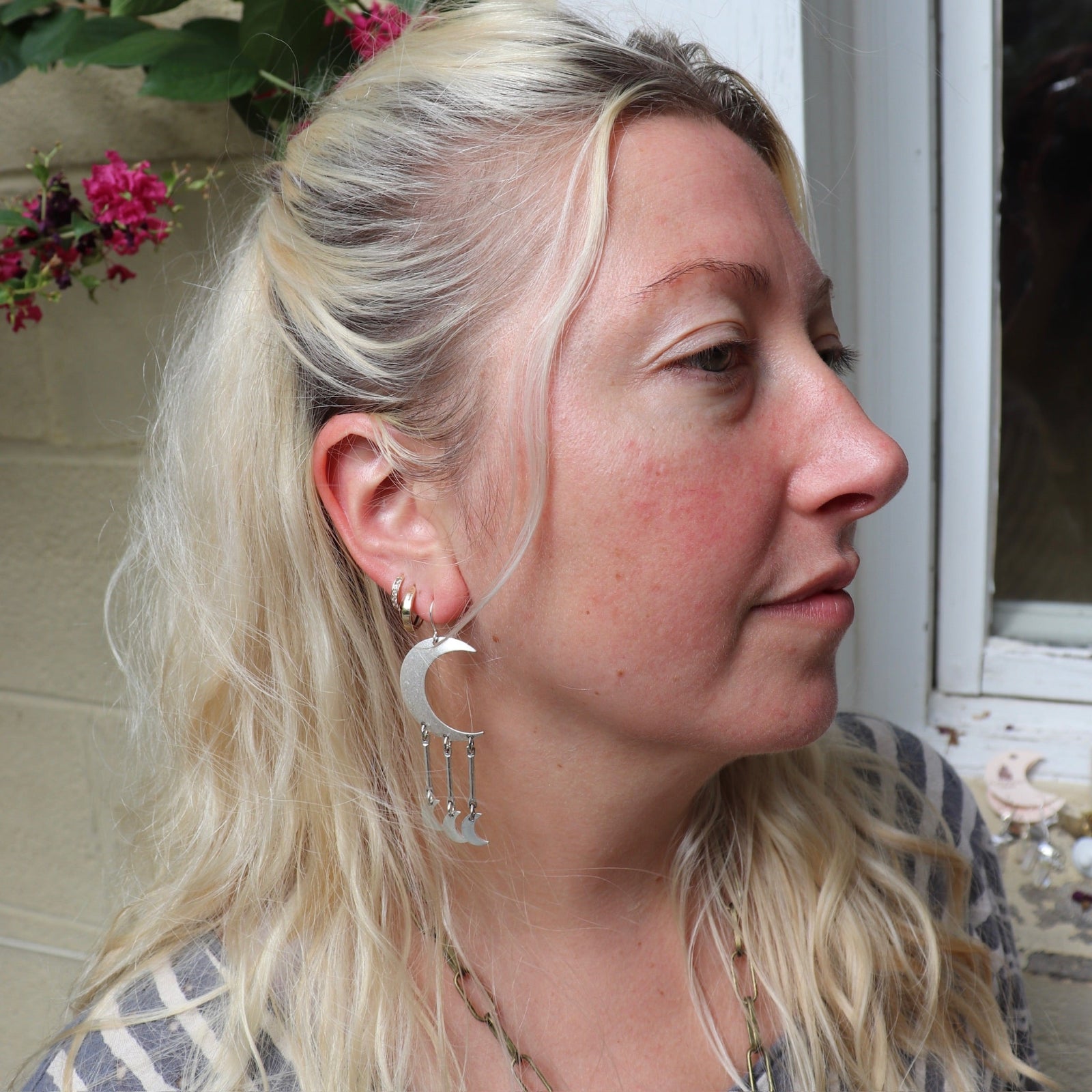 A woman wearing the Silver Many Moons 2.5 inch. Earrings.