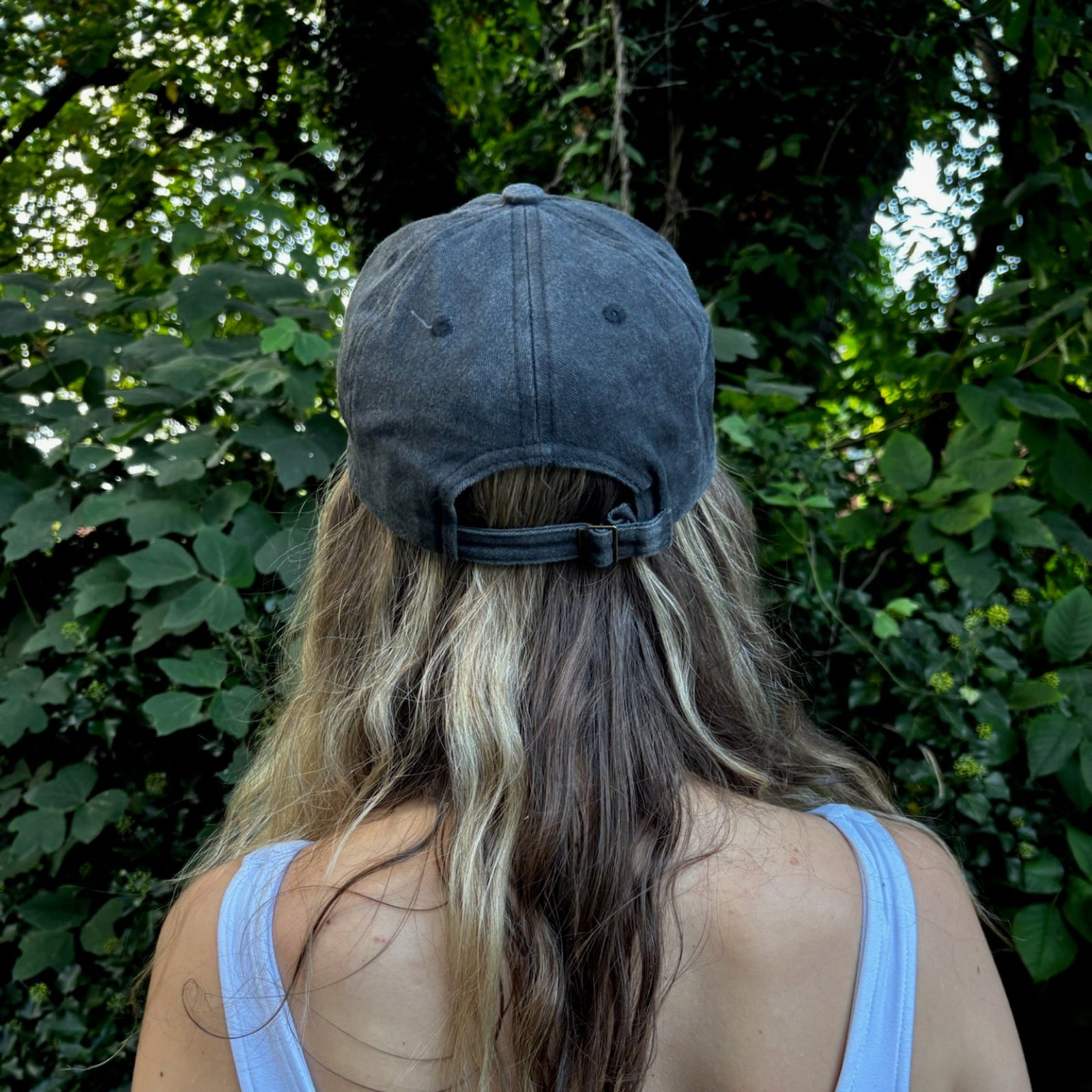 A woman wearing the Flower Garden Embroidered Adjustable Baseball Cap in front of greenery.