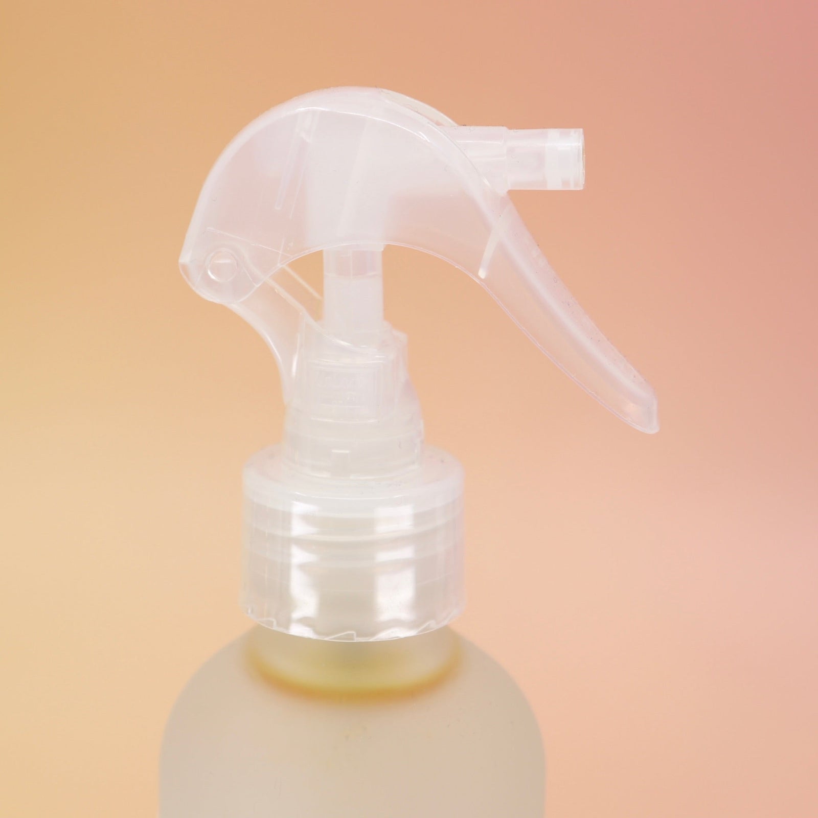An up close image of the Patchouli Vanilla Sea Salt Texturizing Hair Mist and its pump on a pink and yellow background.