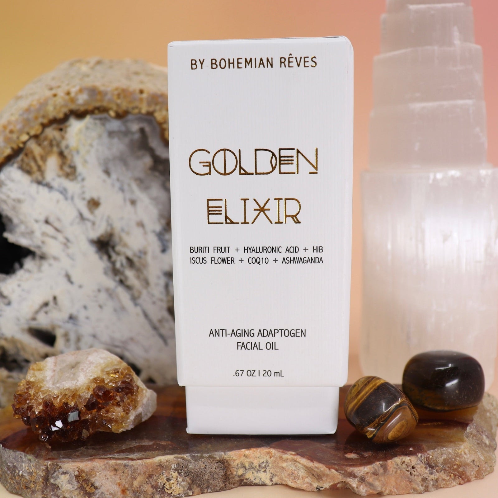 The Anti-Aging Elixir Face Oil from Bohemian Rêves on a slice of agate in front of a open geode and selenite tower, all on a pink and yellow background.