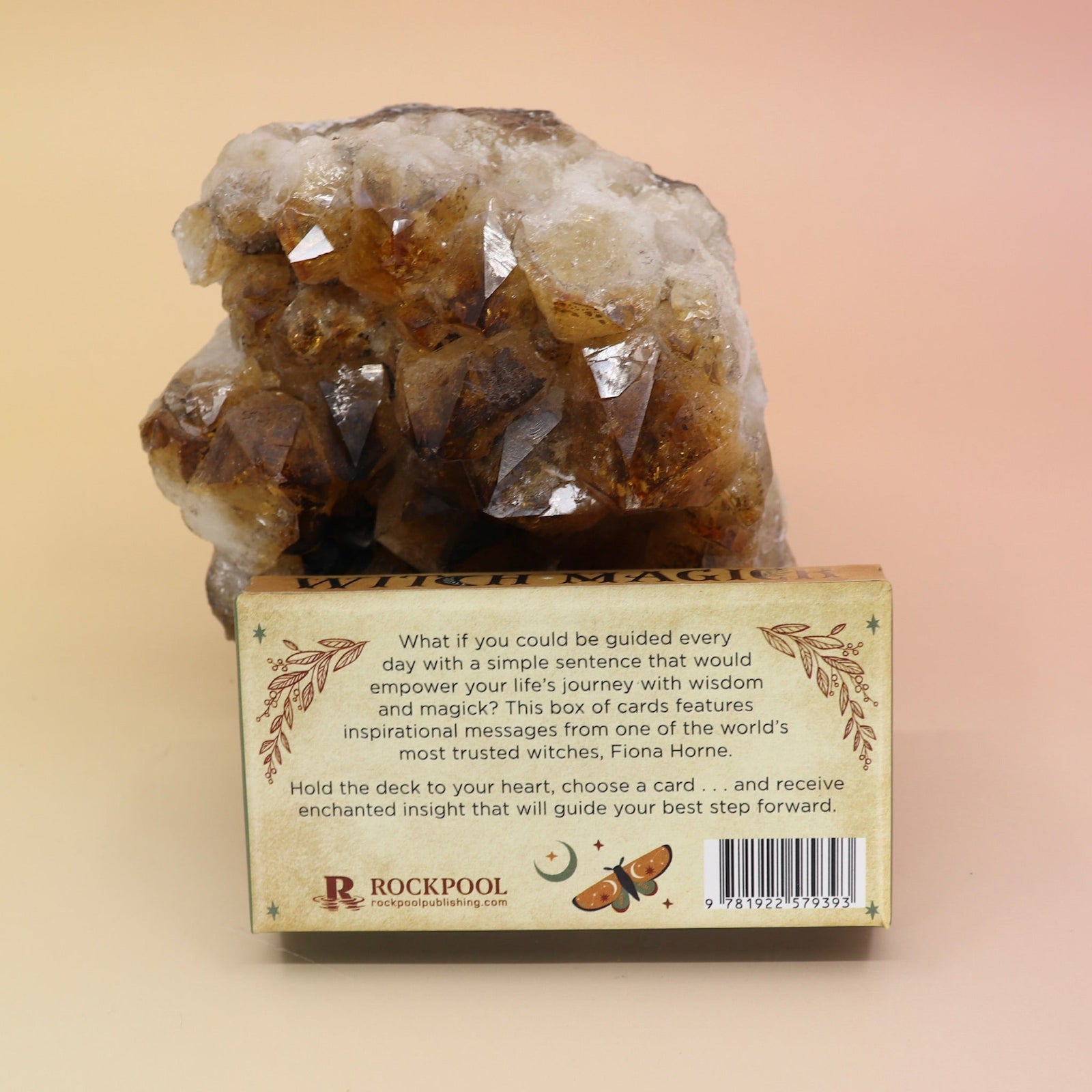 The back of the Witch Magick Affirmation + Divination Cards against a citrine piece all on a pink and yellow background.