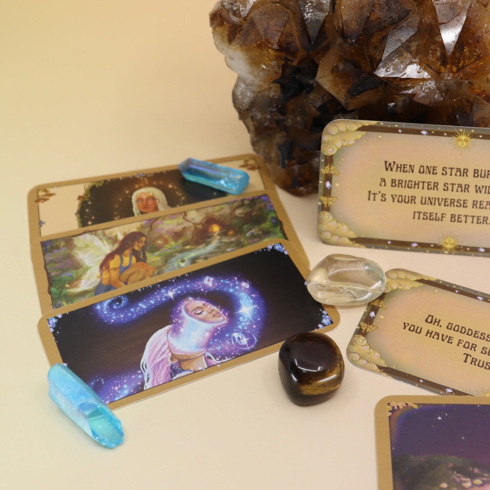 The contents of the Magical Messages from the Universe Affirmation + Divination Cards leaning against a citrine piece all on a pink and yellow background.