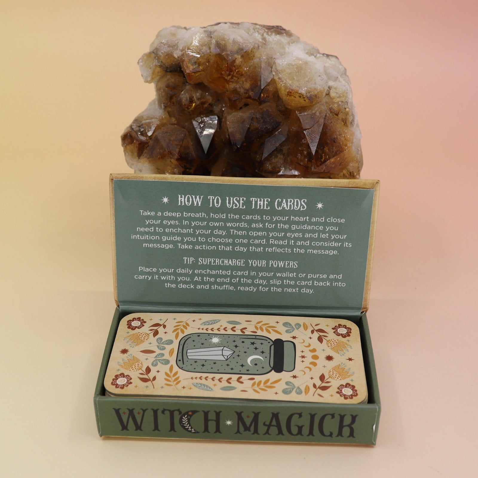 The Witch Magick Affirmation + Divination Cards against a citrine piece all on a pink and yellow background.