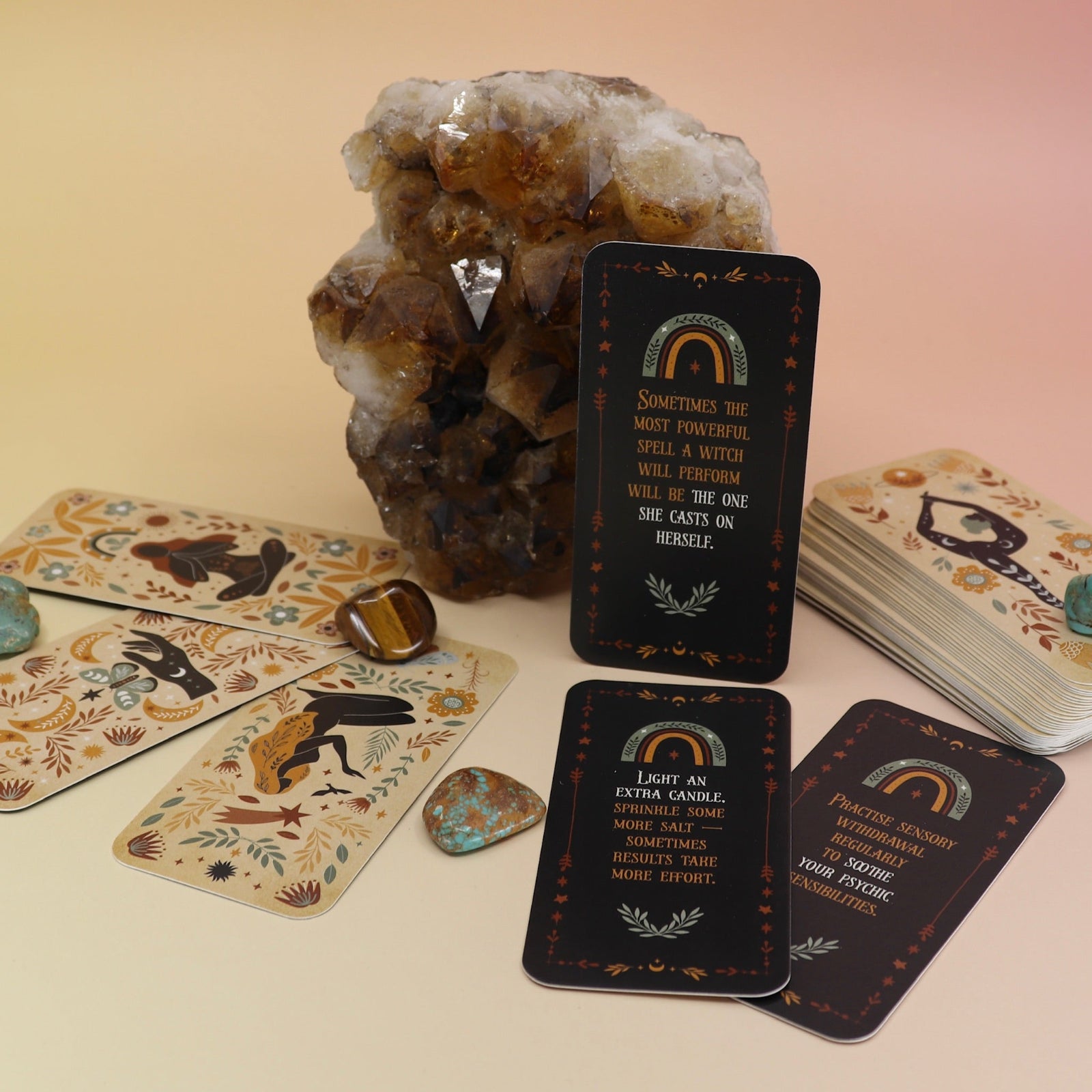 The Witch Magick Affirmation + Divination Cards against a citrine piece and all over on a pink and yellow background.