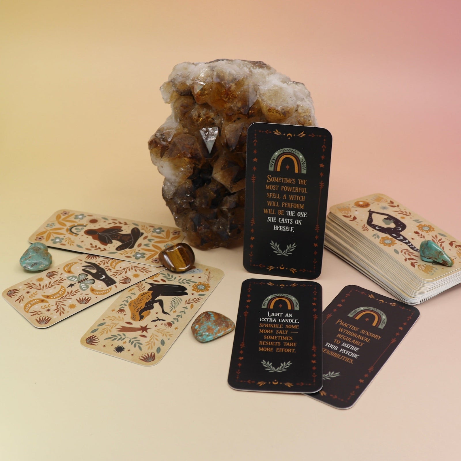 The Witch Magick Affirmation + Divination Cards against a citrine piece and all over on a pink and yellow background.