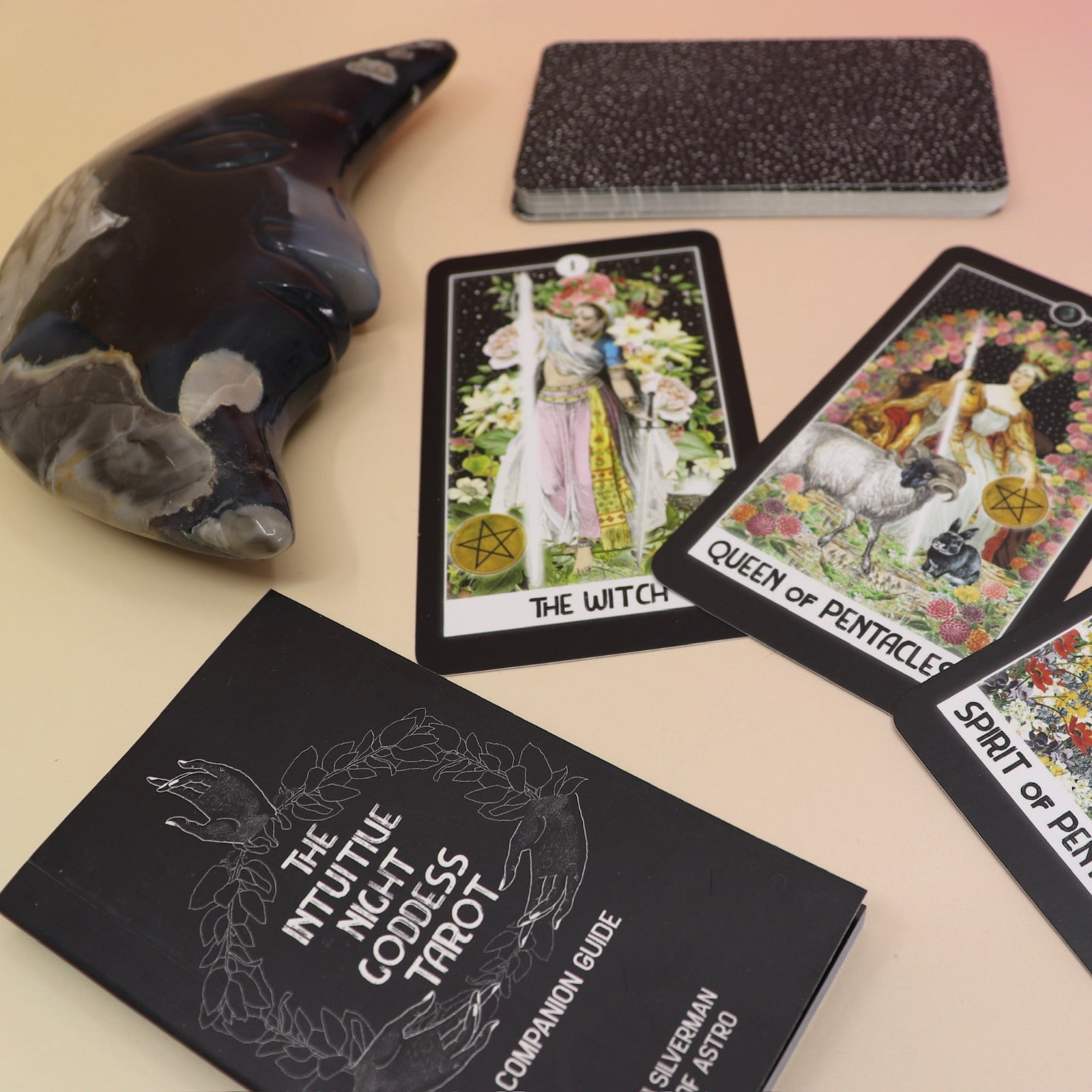The contents of the Intuitive Night Goddess Tarot Deck on a pink and yellow background.