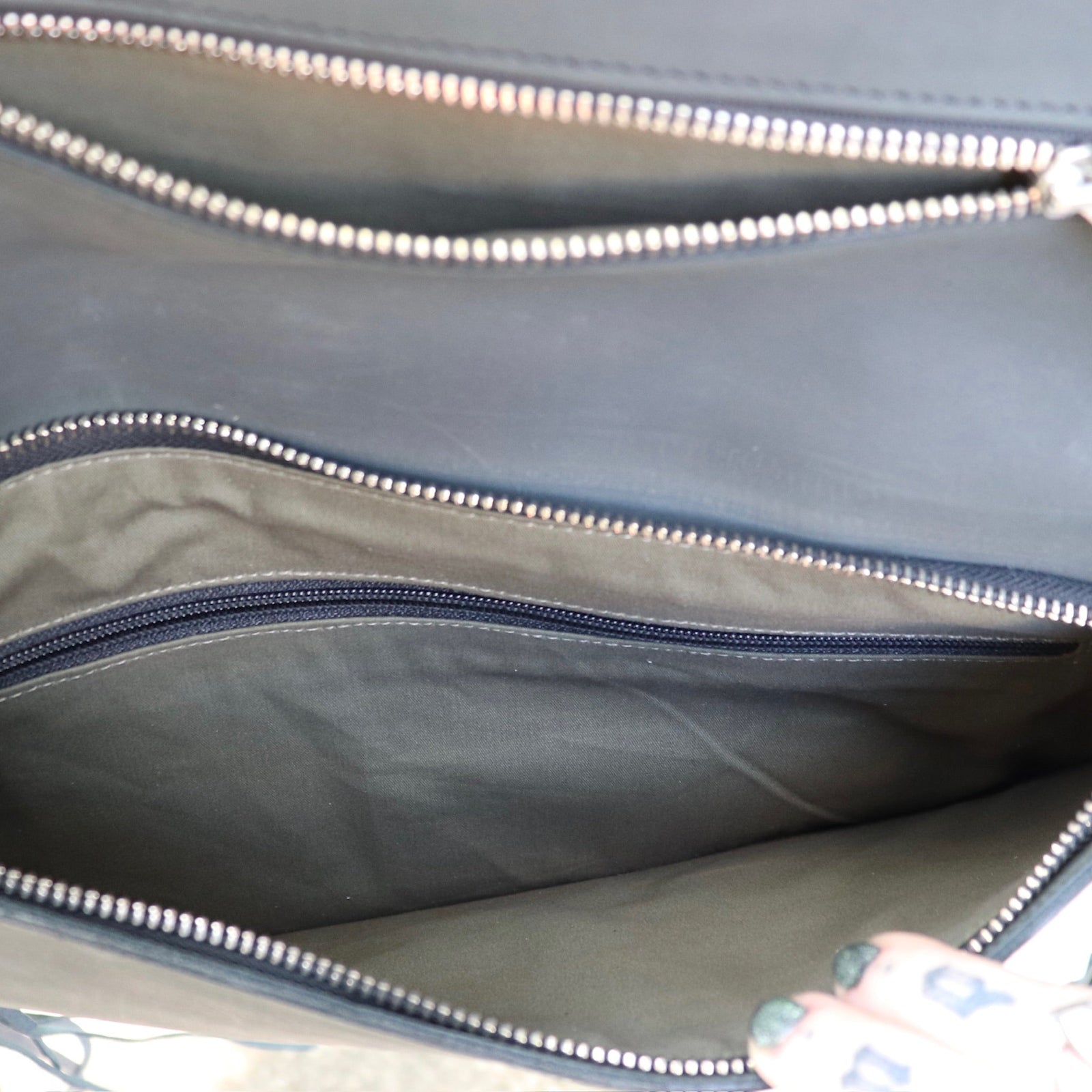 Close-up of a black leather clutch bag with zippers