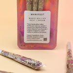 Holographic package of Manifest Magic Rollies with visible herbs inside, surrounded by individual rollies on a soft blush background