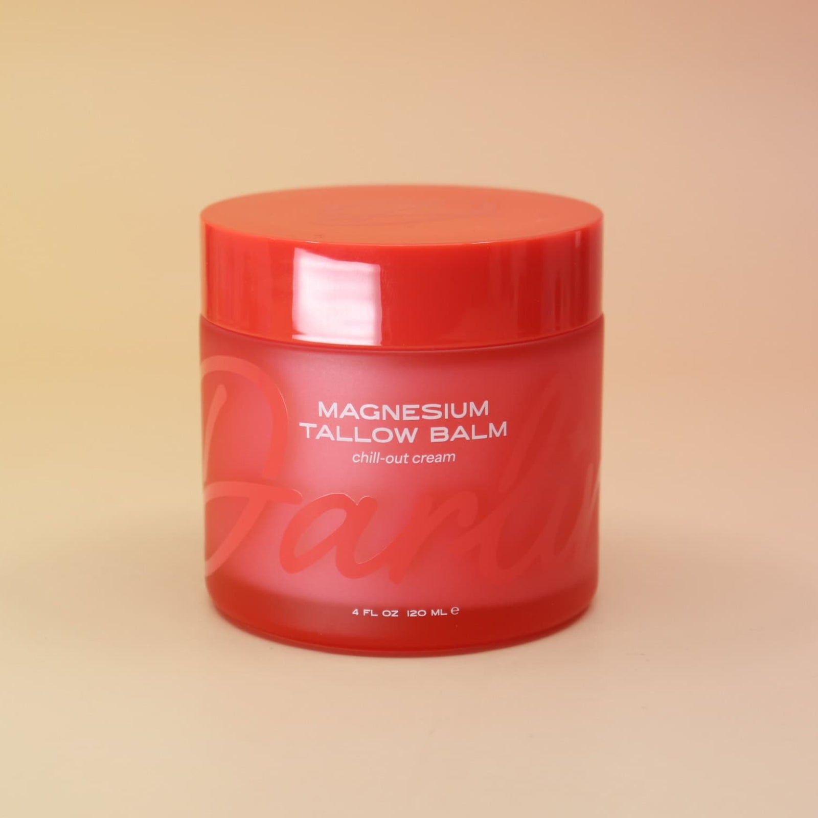 Red jar of magnesium tallow balm on a beige background