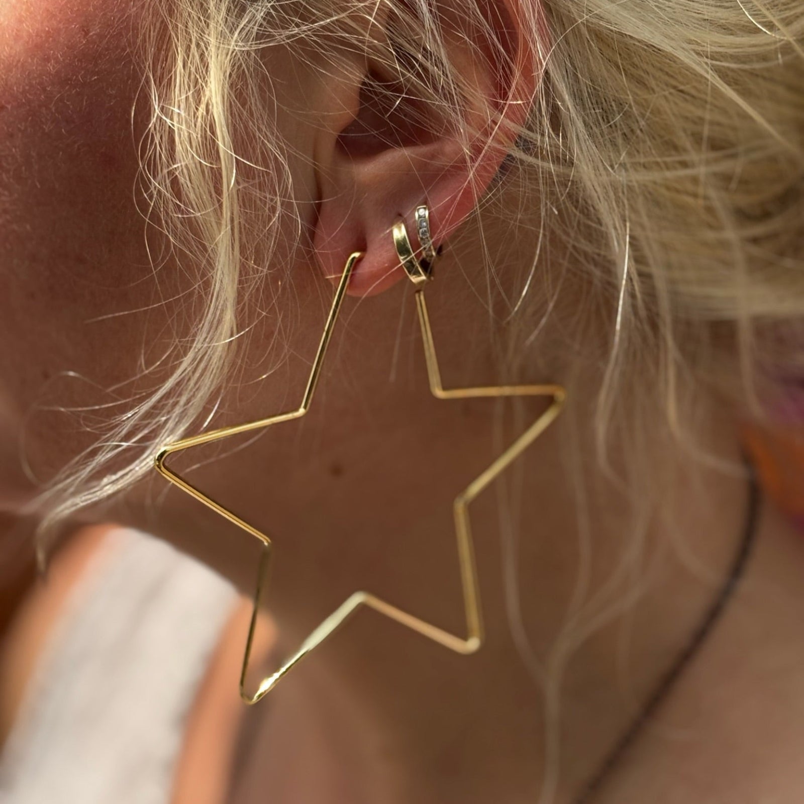 Model wearing oversized gold star hoop earrings