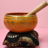 Orange singing bowl with gold accents on a pink background