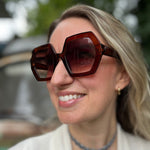 A woman wearing the cognac Iris Seventies Hexagon Sunglasses with a cream kimono.