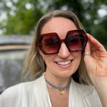 A woman wearing the cognac Iris Seventies Hexagon Sunglasses with a cream kimono.
