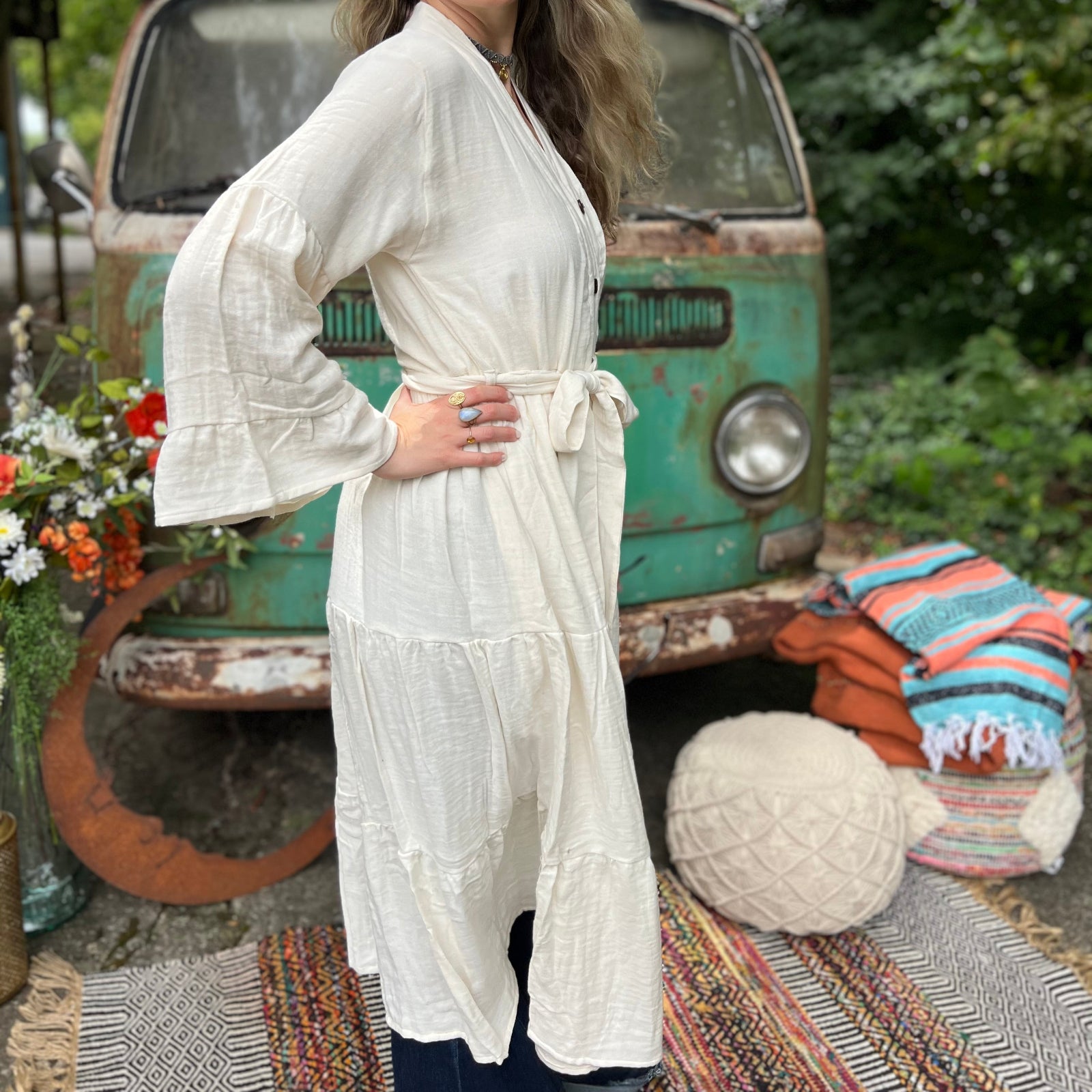 A woman wearing the white Organic Tiered Maxi Kimono Wrap Dress in front of a vintage Volkswagen bus.