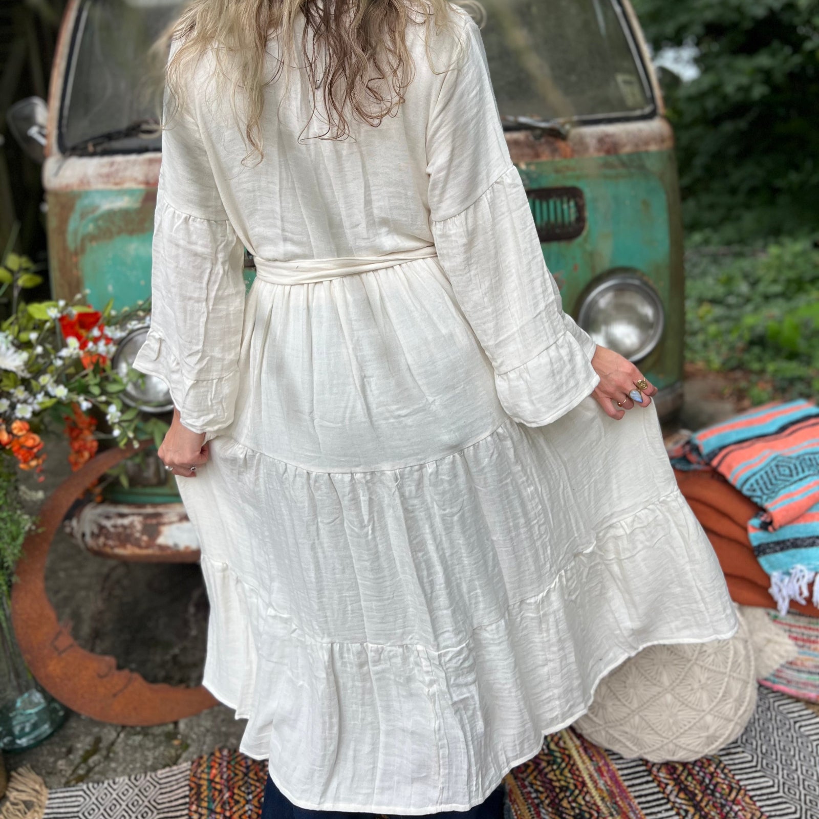 A woman wearing the white Organic Tiered Maxi Kimono Wrap Dress in front of a vintage Volkswagen bus.