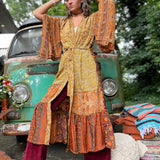 A woman the Hippie Golden Patchwork Kimono Robe Duster with a white bralette and red velvet bellbottoms in front of a vintage Volkswagen bus.