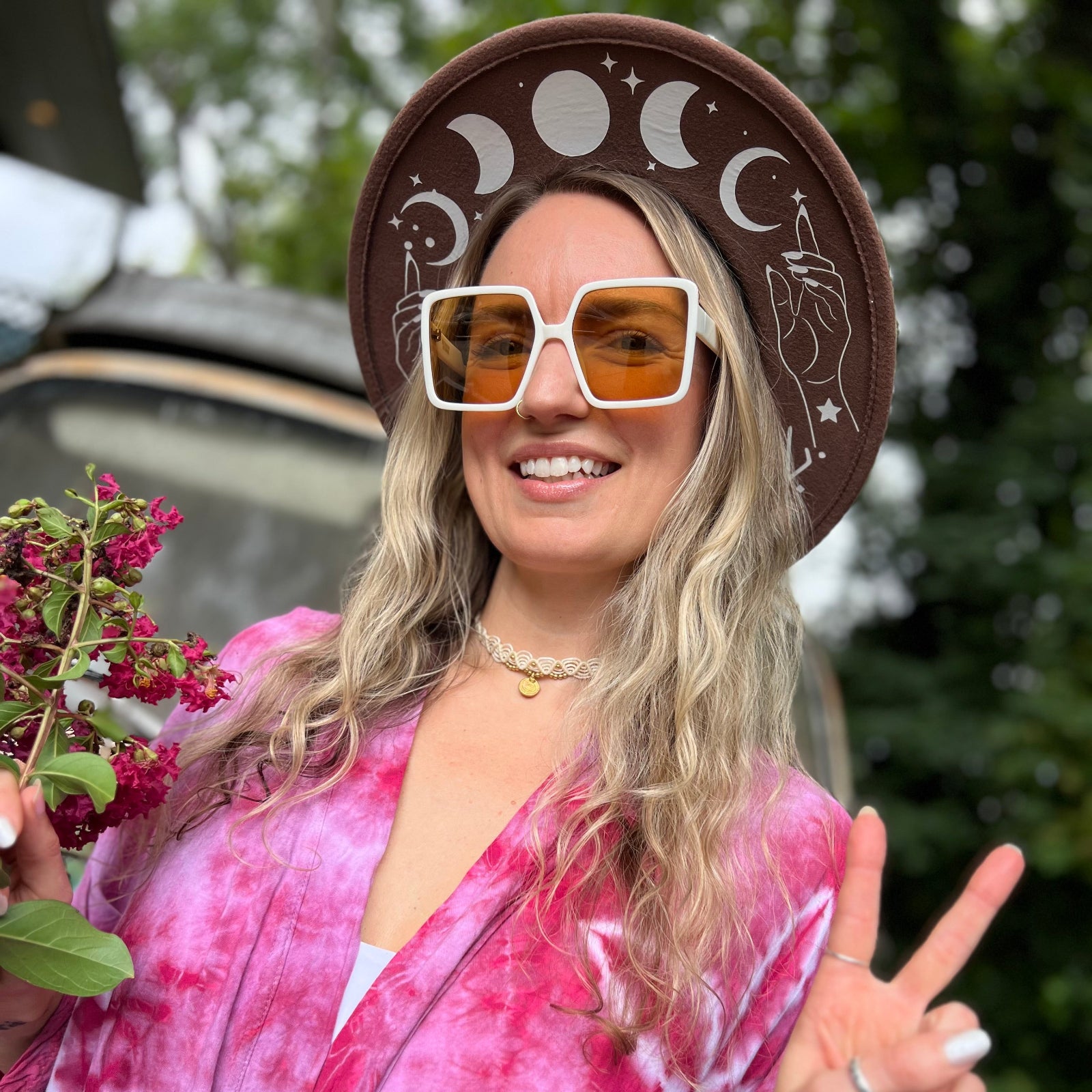 A woman wearing the white Kelso 70s Sunglasses with a brown hat and pink kimono.
