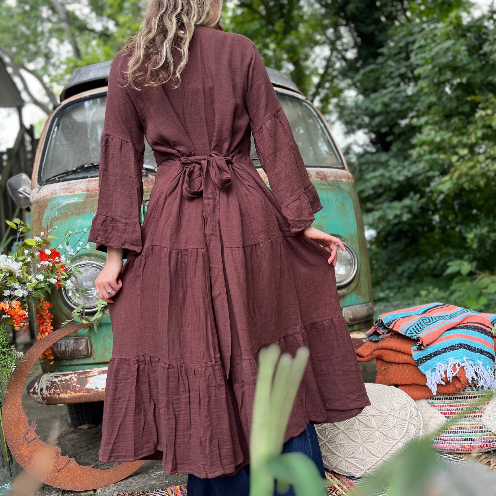 A woman wearing the marron brown Organic Tiered Maxi Kimono Wrap Dress in front of a vintage Volkswagen bus.